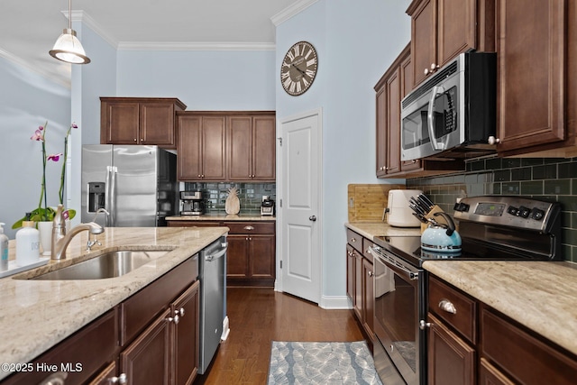 kitchen featuring appliances with stainless steel finishes, dark wood-type flooring, light stone countertops, crown molding, and a sink