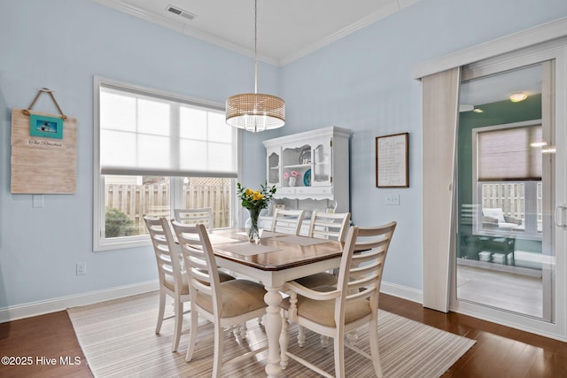 dining room featuring visible vents, crown molding, baseboards, and wood finished floors