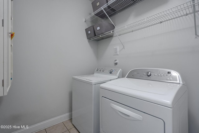 laundry area with laundry area, light tile patterned floors, baseboards, and separate washer and dryer