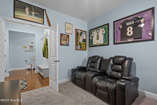 carpeted cinema room featuring wood finished floors and baseboards