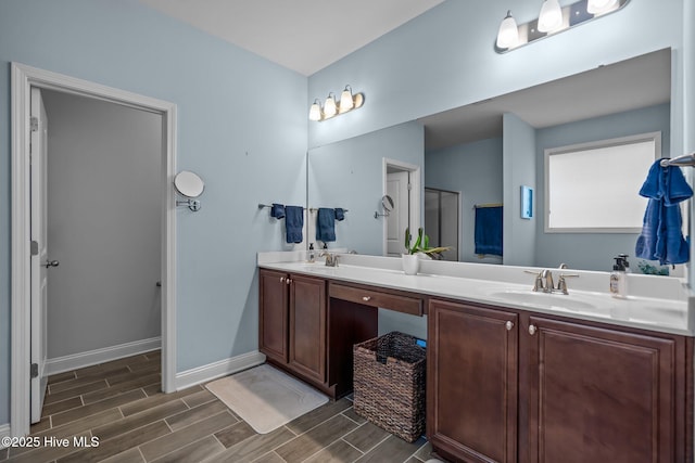 bathroom featuring double vanity, wood finish floors, and a sink