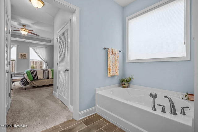 full bathroom featuring a garden tub, ceiling fan, baseboards, and ensuite bathroom