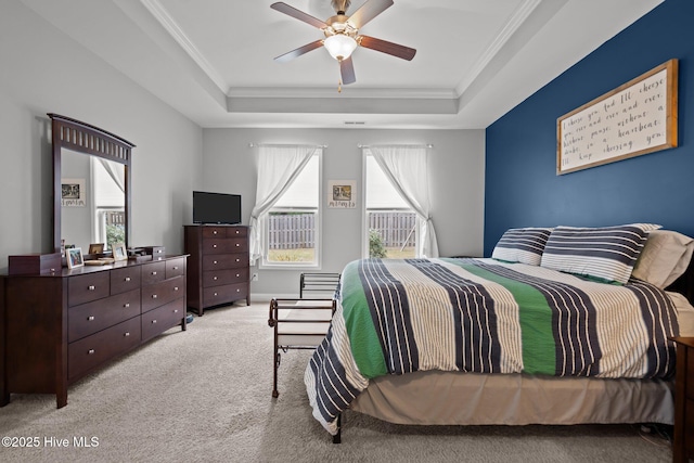 carpeted bedroom featuring ceiling fan, a tray ceiling, and crown molding