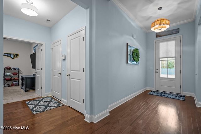 foyer with crown molding, visible vents, baseboards, and wood finished floors