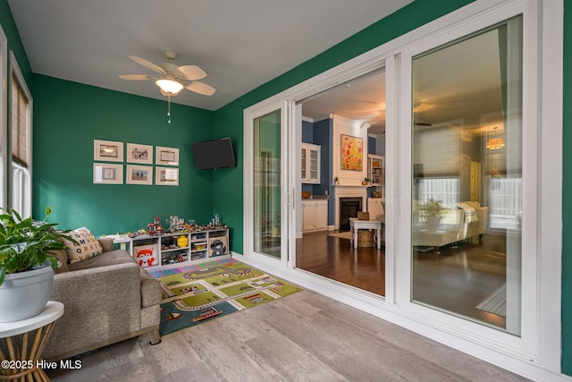 playroom featuring ceiling fan, a fireplace, and wood finished floors