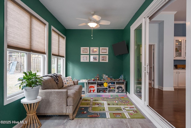 recreation room featuring ceiling fan, baseboards, and wood finished floors