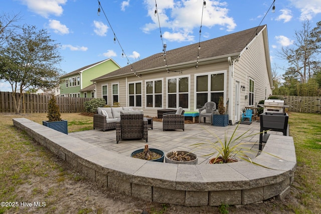 back of house featuring roof with shingles, a fenced backyard, a patio, and an outdoor hangout area