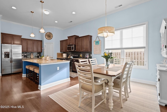 dining space with baseboards, visible vents, ornamental molding, light wood-type flooring, and recessed lighting