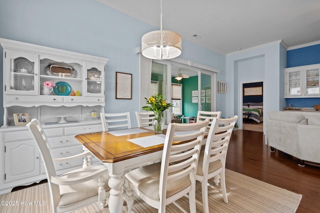 dining room with a notable chandelier, crown molding, visible vents, and wood finished floors