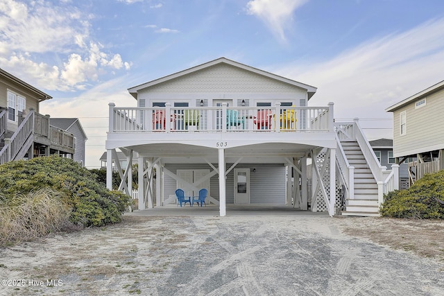 coastal home with stairs, a carport, and driveway