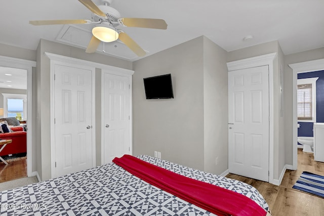 bedroom featuring a closet, attic access, ceiling fan, wood finished floors, and baseboards