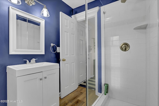 bathroom featuring tiled shower, vanity, and wood finished floors