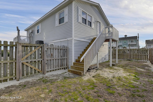 view of property exterior featuring stairway, a fenced backyard, and a gate