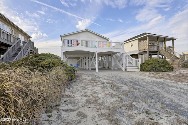 coastal inspired home featuring driveway, stairs, and a carport