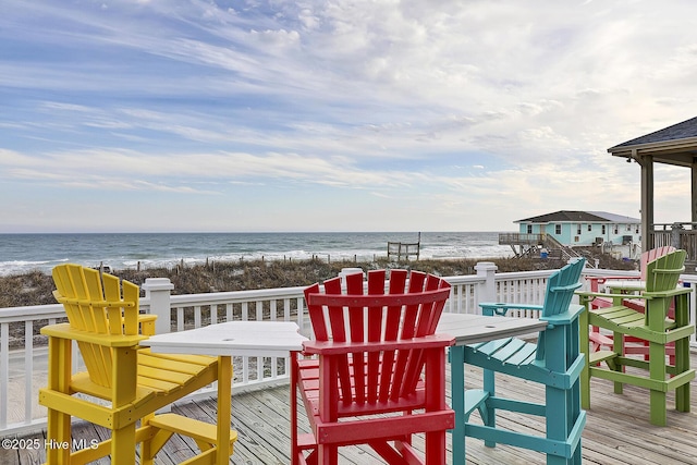 wooden terrace featuring a water view and a view of the beach