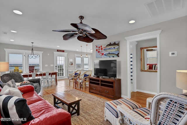 living room featuring recessed lighting, visible vents, light wood-style flooring, and ceiling fan with notable chandelier