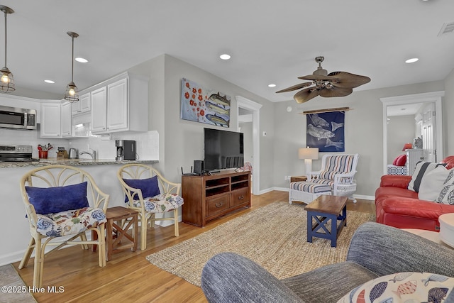 living area with light wood-type flooring, visible vents, a ceiling fan, and recessed lighting