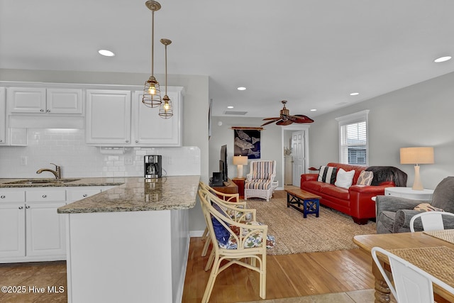 kitchen featuring open floor plan, a sink, white cabinetry, and decorative backsplash