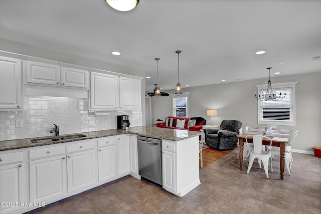 kitchen with backsplash, stainless steel dishwasher, white cabinetry, a sink, and a peninsula