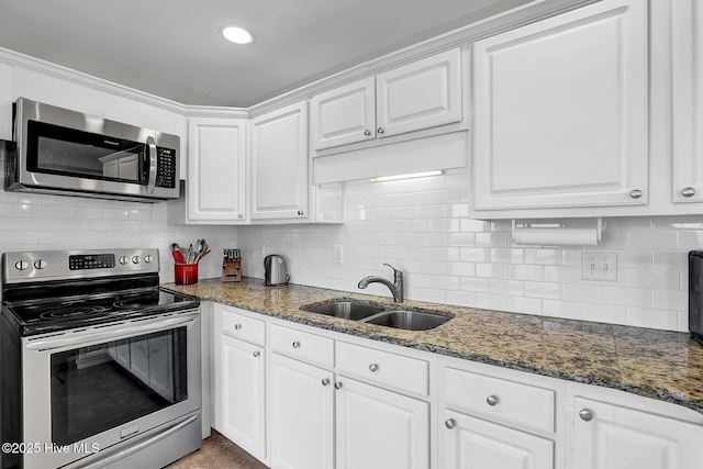 kitchen featuring appliances with stainless steel finishes, white cabinetry, a sink, and decorative backsplash