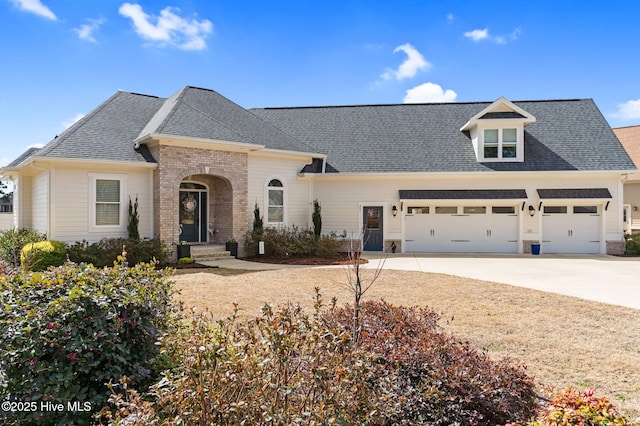 view of front facade with concrete driveway, brick siding, a garage, and a shingled roof