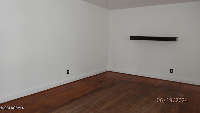 spare room featuring baseboards and wood finished floors