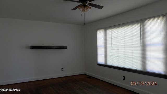 empty room with visible vents, wood finished floors, a ceiling fan, and baseboards