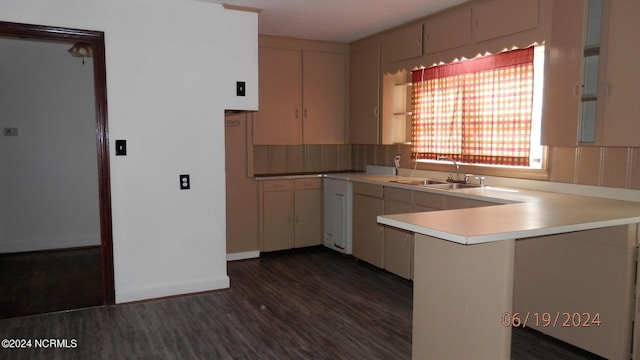 kitchen with a peninsula, dark wood finished floors, light countertops, and a sink