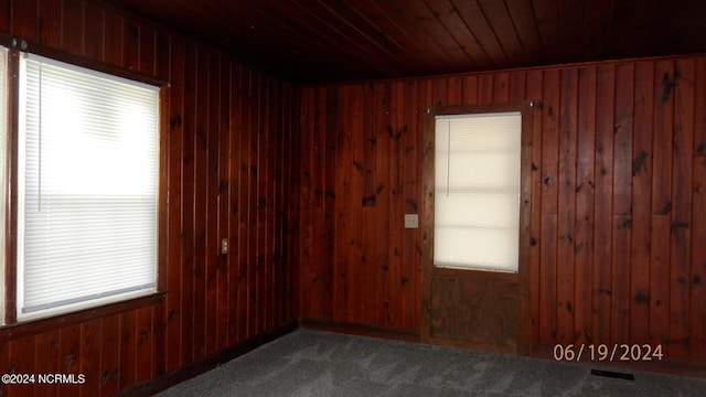 unfurnished room featuring wood ceiling and wooden walls