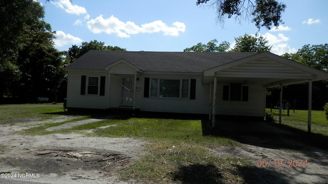 view of front facade featuring a shingled roof, driveway, a carport, and a front lawn