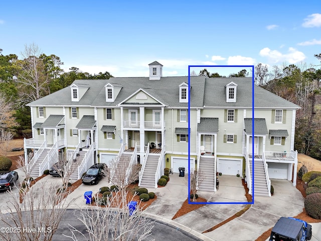 view of property with a residential view, concrete driveway, stairs, and an attached garage