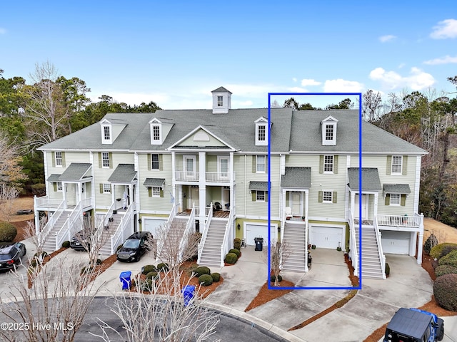 view of front facade with stairs, driveway, an attached garage, and a residential view