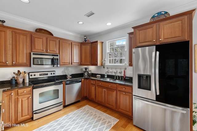 kitchen featuring appliances with stainless steel finishes, brown cabinetry, visible vents, and a sink