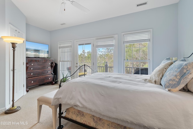 carpeted bedroom with access to outside, visible vents, and a ceiling fan