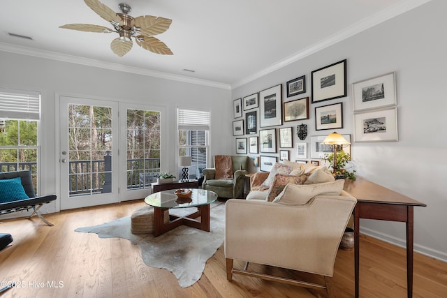 living room with a wealth of natural light, wood finished floors, visible vents, and crown molding