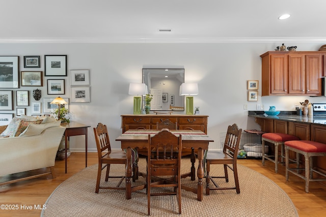 dining space with ornamental molding, recessed lighting, visible vents, and light wood-style flooring