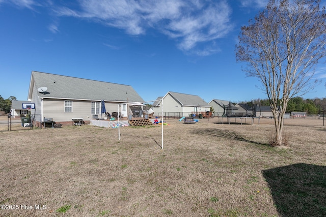 view of yard featuring a trampoline, fence, and a wooden deck