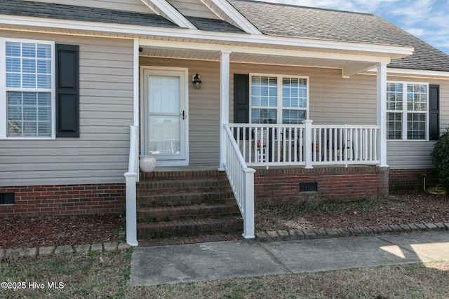 view of exterior entry with covered porch, roof with shingles, and crawl space