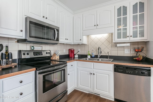 kitchen featuring dark wood-style flooring, a sink, stainless steel appliances, glass insert cabinets, and white cabinetry