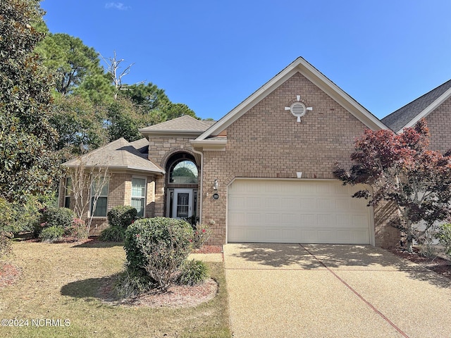 view of front facade with brick siding, an attached garage, driveway, and a shingled roof