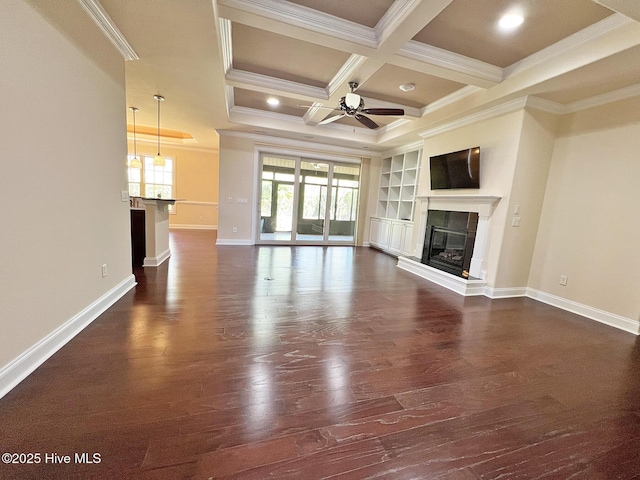 unfurnished living room with ornamental molding, a tiled fireplace, a ceiling fan, coffered ceiling, and dark wood finished floors