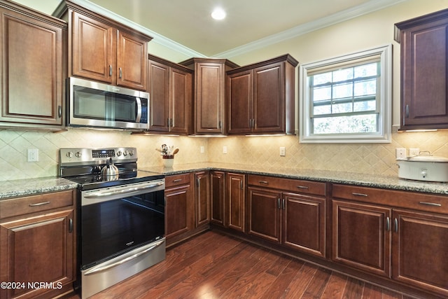 kitchen with stone counters, appliances with stainless steel finishes, ornamental molding, and dark wood-style flooring