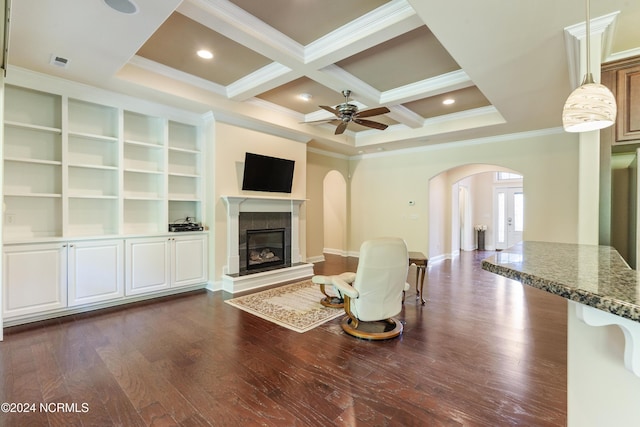 living area with dark wood-type flooring, a tile fireplace, arched walkways, coffered ceiling, and a ceiling fan