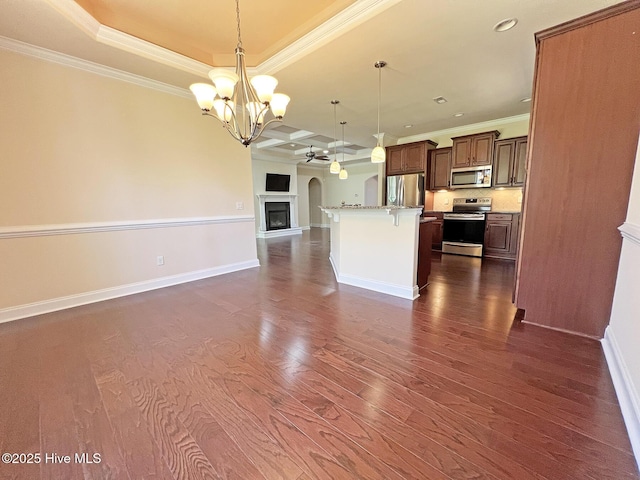 kitchen with open floor plan, appliances with stainless steel finishes, crown molding, baseboards, and dark wood-style flooring