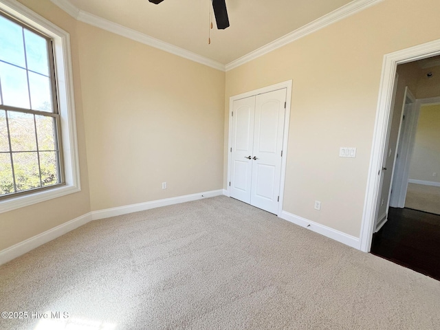 unfurnished bedroom featuring ornamental molding, a closet, carpet, baseboards, and ceiling fan