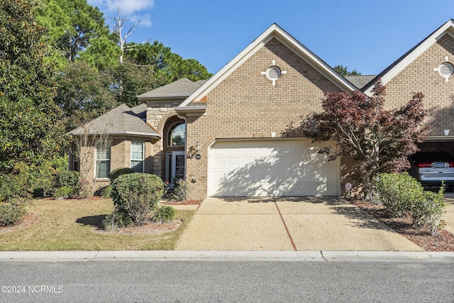 view of front of property featuring brick siding, an attached garage, and driveway