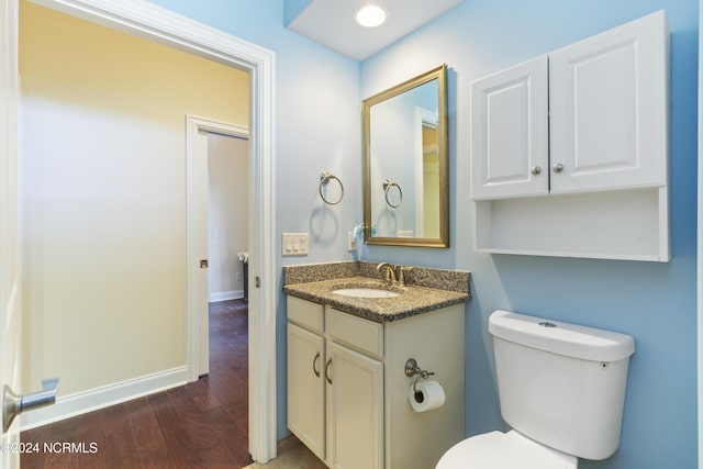 bathroom with baseboards, toilet, wood finished floors, and vanity