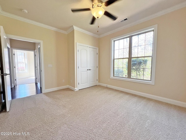 unfurnished bedroom featuring visible vents, multiple windows, light colored carpet, and crown molding