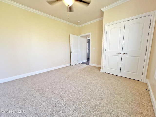 unfurnished bedroom featuring light carpet, a ceiling fan, a closet, crown molding, and baseboards