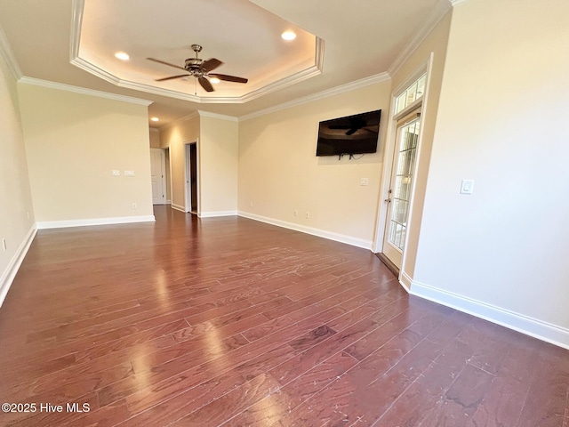 empty room featuring dark wood finished floors, a raised ceiling, ornamental molding, and ceiling fan